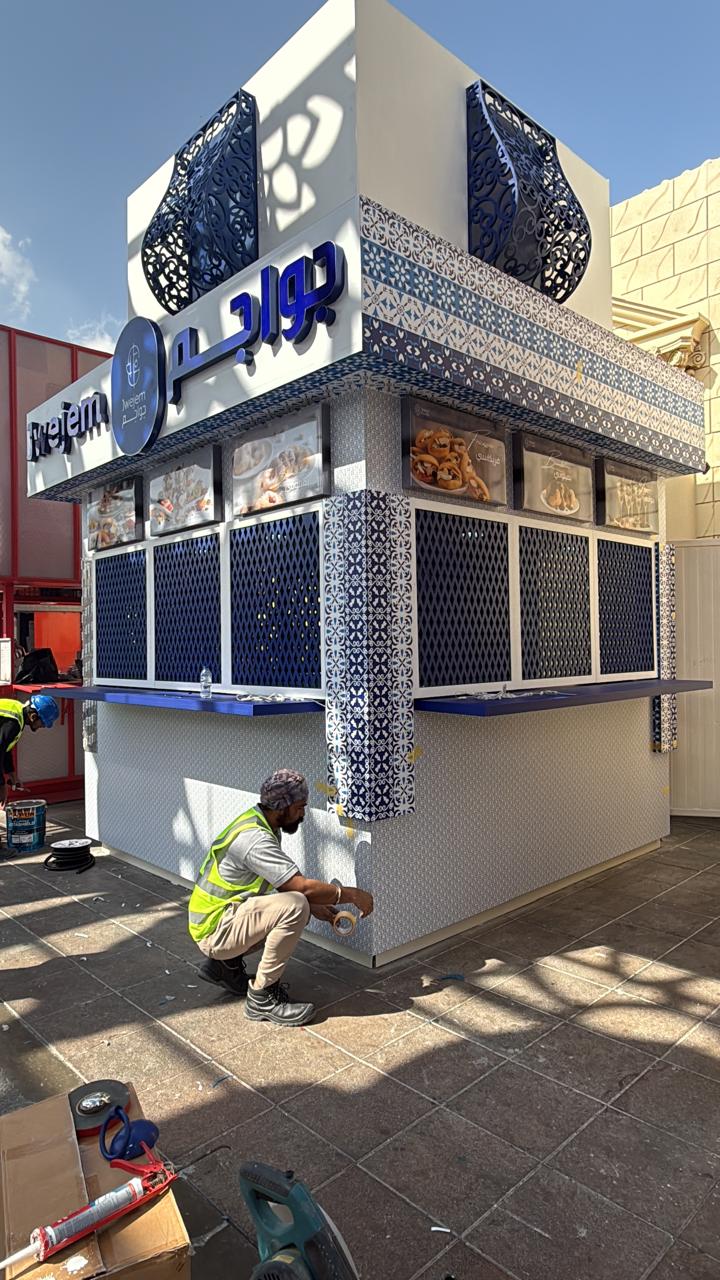 Kiosk with blue patterned tile cladding and screen panels being finished