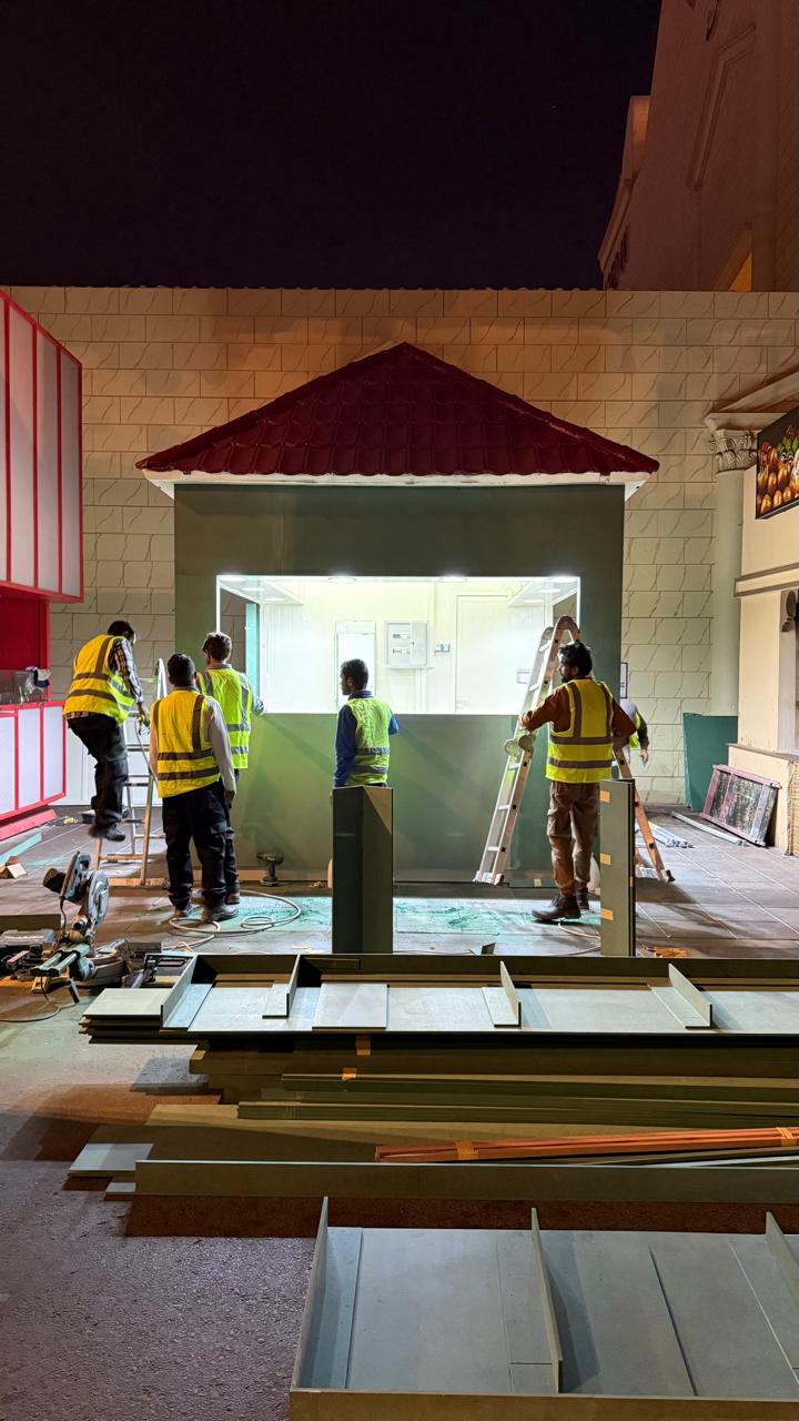 Team assembling the kiosk frame at Global Village at night